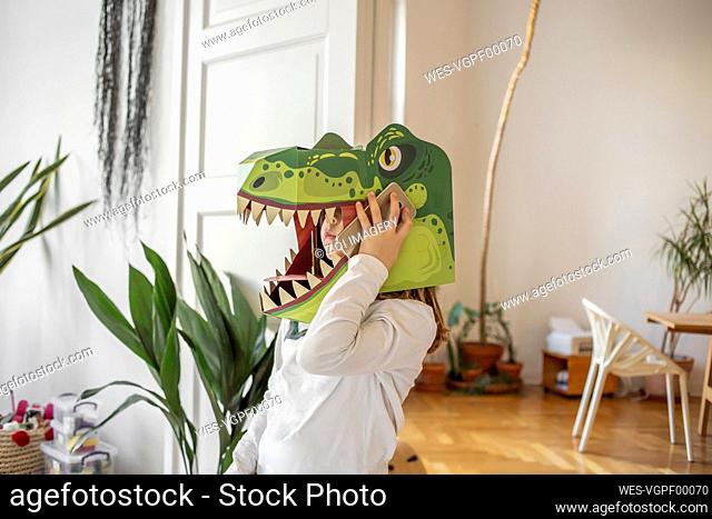 Girl with Dinosaur mask talking on smart phone at home