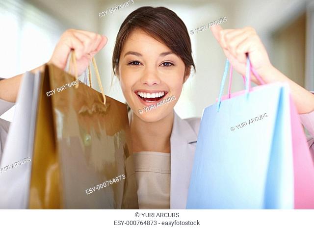 Happy excited young female holding up her shopping bags