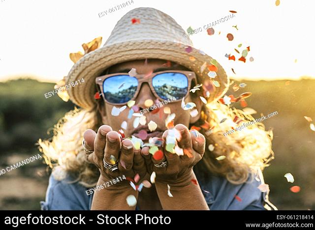 beautiful defocused woman blow confetti from hands. celebration and event concept. happiness and coloured image. movement and happiness for active people...
