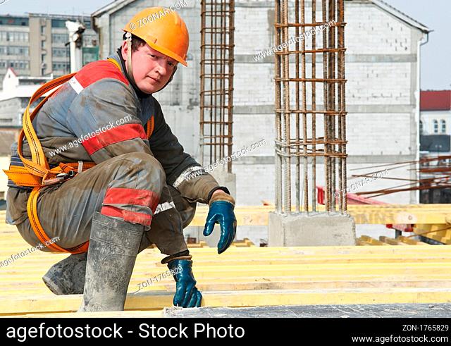 Young builder worker in work wear, helmet and equipment at house building area