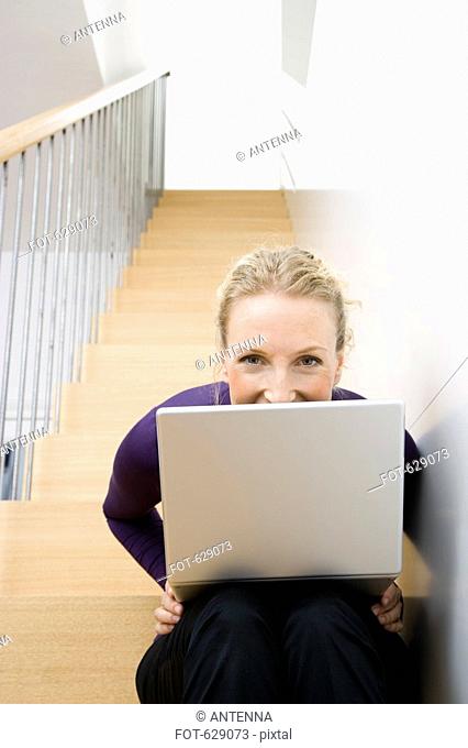 A mid adult woman sitting on a staircase using a laptop