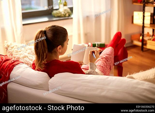 woman writing to notebook at home on christmas