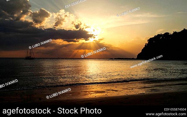 Tranquil beach with silhouette of ship on the sea in background, during golden sunset light. Kantiang Bay, Koh Lanta, Thailand
