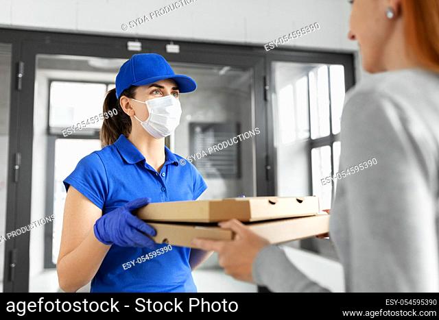 delivery girl in mask giving pizza boxes to woman