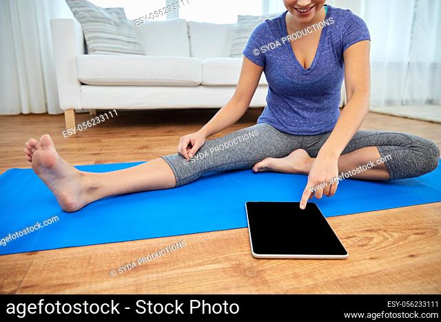 woman with tablet pc computer doing yoga at home