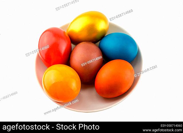 Six bright orange eggs and gold lie on a ceramic saucer on a white isolated background