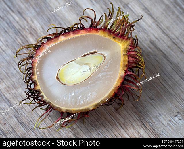 Half of a rambutan on a wooden background. Close up view