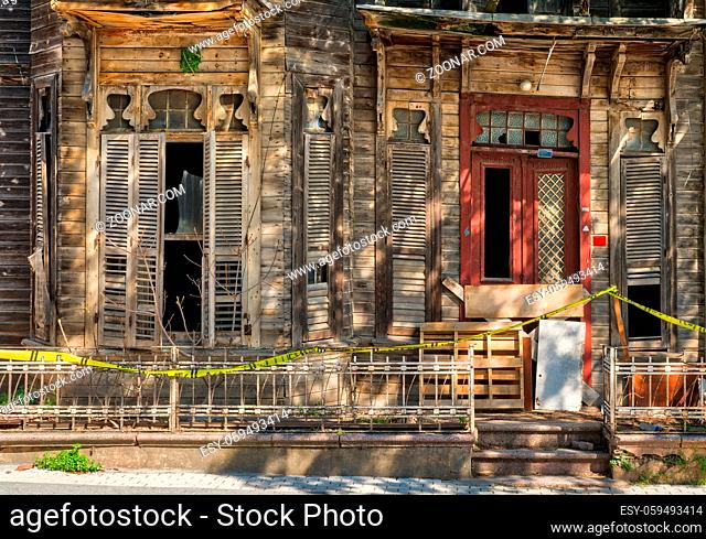 Vintage door and window on abandoned wooden house with small balcony and rusted metal fence on street level