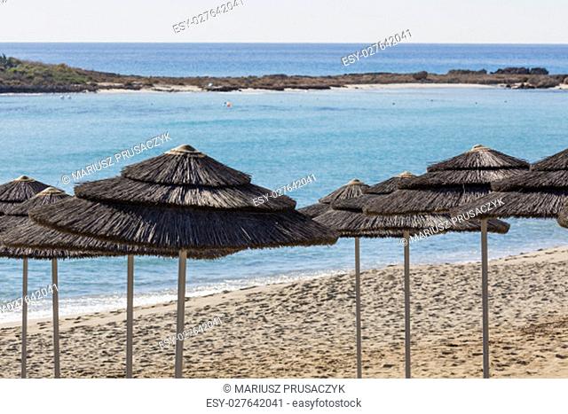 Detail of woven umbrellas above rows on beach in Cyprus