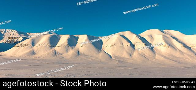 Arctic winter landscape with snow covered mountains and blue sky on a sunny day at Svalbard, Norway