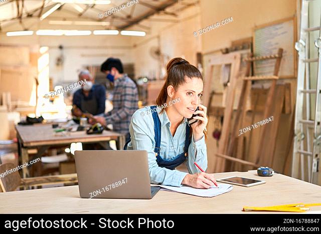 Handwerker Frau bei Kundengespräch am Telefon in einer Schreinerei Werkstatt