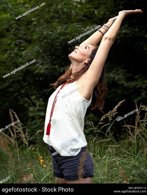 Woman stretching arms in forest