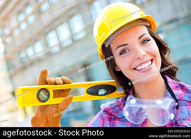 Portrait of Young Attractive Female Construction Worker with Level Wearing Gloves, Hard Hat and Protective Goggles at Construction Site