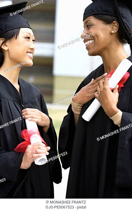 Graduates in caps and gowns holding diplomas