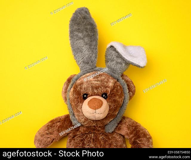 cute brown teddy bear wearing a rabbit mask with long ears on his head, funny holiday Easter card