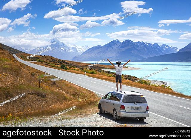 Guy on a car roof, Lake Pukaki, Mount Cook, Canterbury region, Mackenzie District, South Island, New Zealand, Oceania