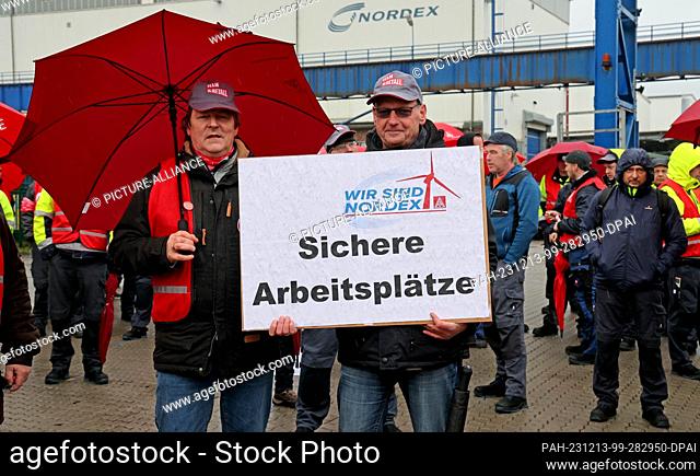 13 December 2023, Mecklenburg-Western Pomerania, Rostock: An employee of wind turbine manufacturer Nordex Energy holds a sign reading ""Secure jobs"" during a...