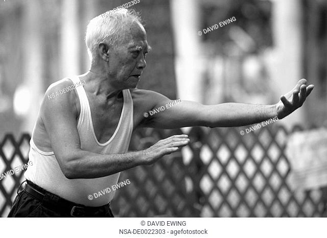 An Elderly Man Practices Tai Chi in a Park in Hong Kong