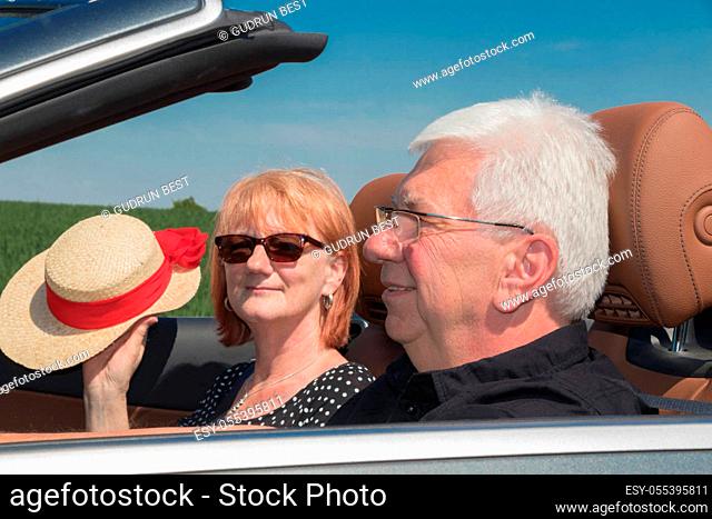 Older couple in a luxury convertible car on a sunny day