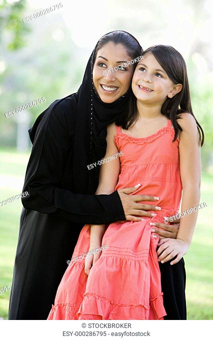 Woman and young girl outdoors in a park smiling selective focus