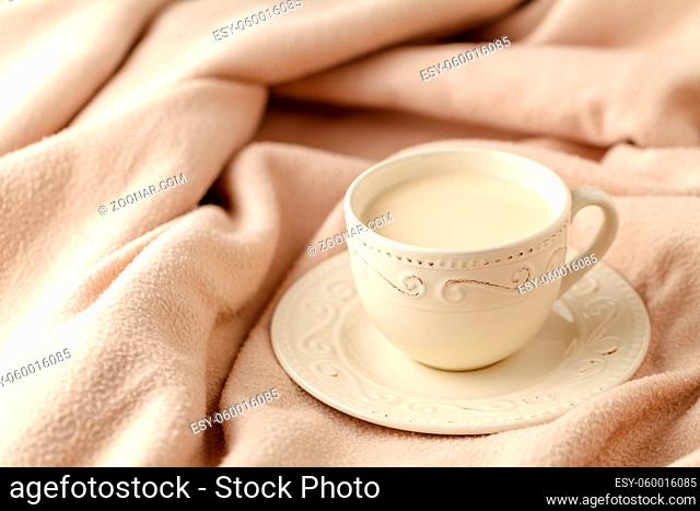 Cup of hot tea with lemon dressed in knitted warm winter scarf on wool, soft focus