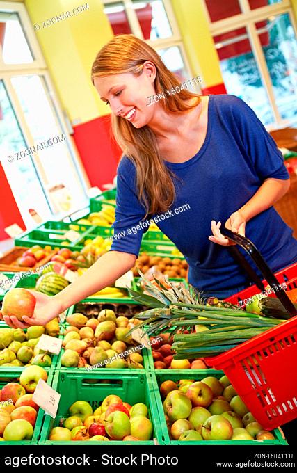 Lachende junge Frau kauft Äpfel im Bio-Supermarkt