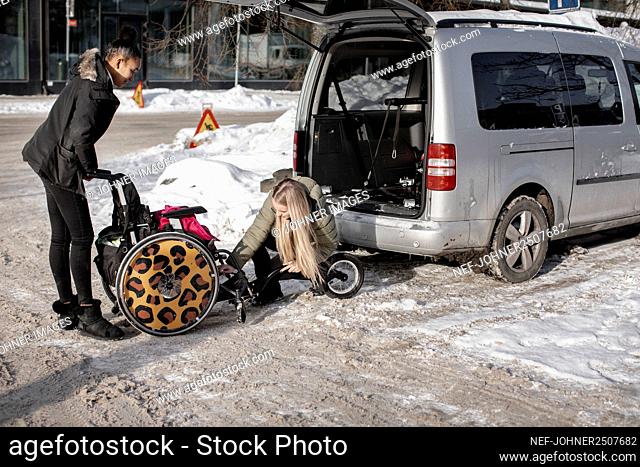 Women putting wheelchair into van