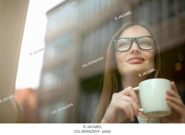 Businesswoman with coffee cup at cafe window, Freiburg, Germany