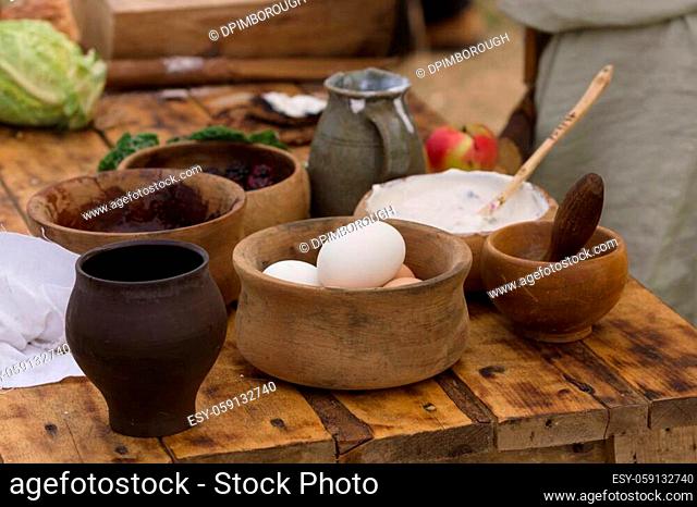 Medieval food preparation including eggs, cream and fruit in wooden bowls or trenchers