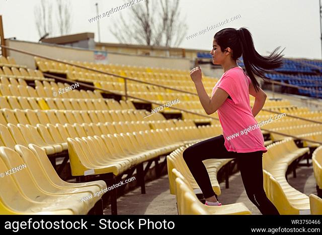 Side view of a woman running on stadium staircase