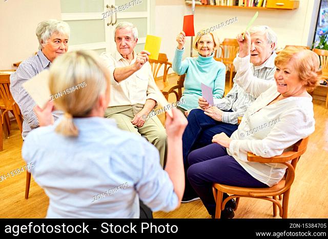 Therapeutin und Senioren machen Denkspiel mit bunten Zetteln als Gedächtnistraining