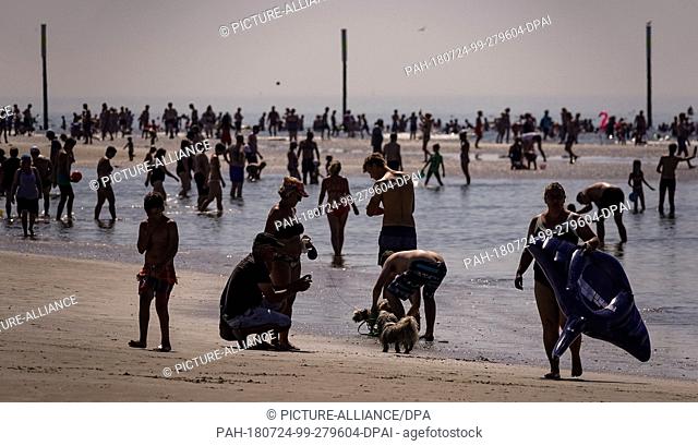 24 July 2018, Germany, Sankt Peter Ording: Beach guests search for refreshment in the water. Photo: Axel Heimken/dpa. - Sankt...