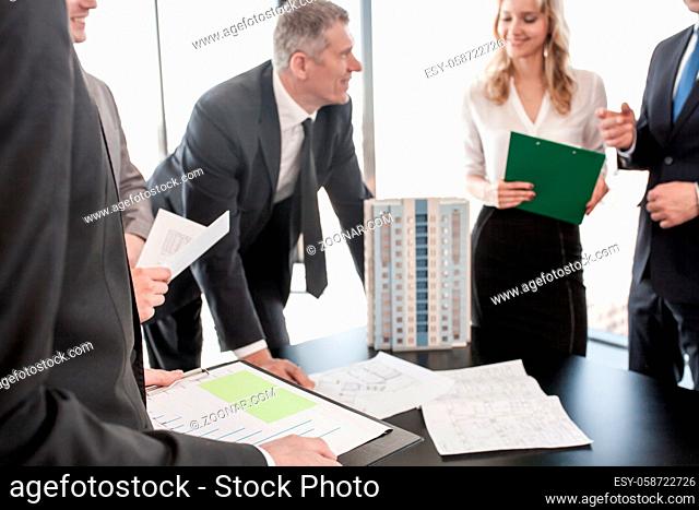 Business meeting of architects and investors, model of modern multi storey residential building house on table , construction planning concept
