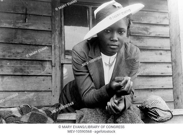 Migratory agricultural worker from Florida waiting to leave Belcross, North Carolina to another job at Onley, Virginia. It is Sunday and she is wearing her best...