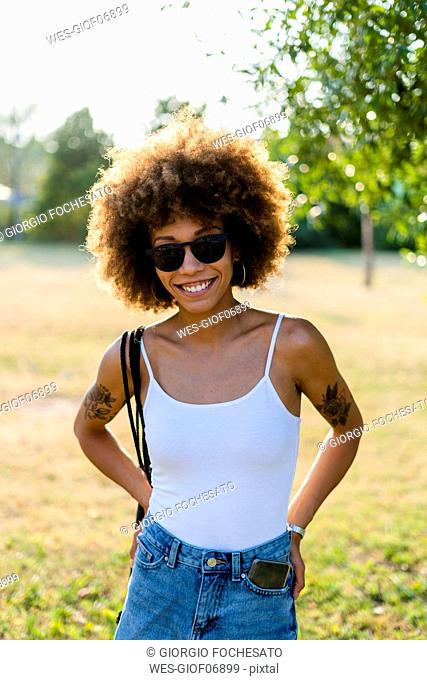 Portrait of tattooed young woman with smartphone in her trouser pocket