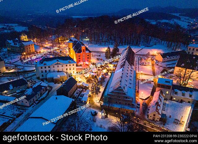 08 December 2023, Saxony, Königstein: The stalls at the Christmas market at Königstein Fortress are brightly lit (aerial view taken with a drone)