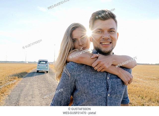 Portrait of happy young couple at camper van in rural landscape