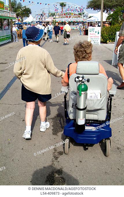 Handicapped person with oxygen tank in motorized wheelchair