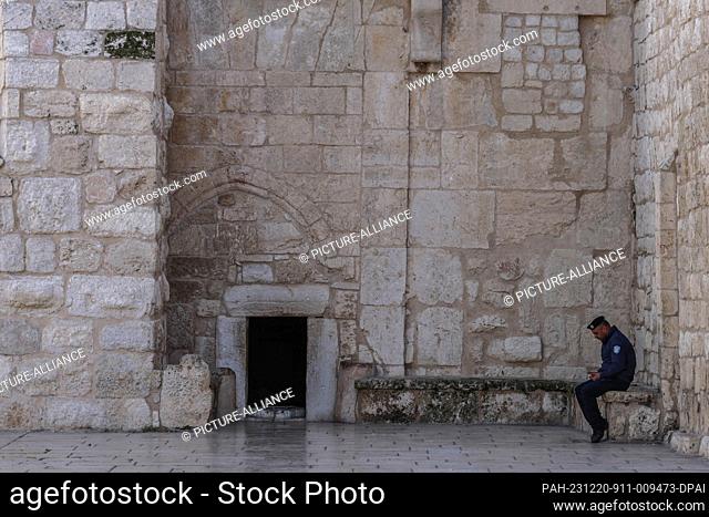 20 December 2023, Palestinian Territories, Bethlehem: A policeman sits outside the entrance to the Al-Mahd Church, which is devoid of visitors after Christmas...