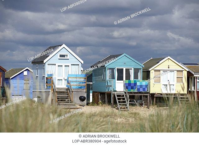 England, Dorset, Mudeford, A view through long grass towards beach huts on the seafront at Mudeford, two miles from Christchurch