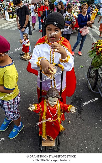 A Child In Costume Waits With His Santo Nino Statue For The Arrival By Sea Of The Replica Santo Nino De Cebu, The Fluvial Procession, Dinagyang Festival, Iloilo