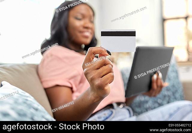 happy woman with tablet pc and credit card at home
