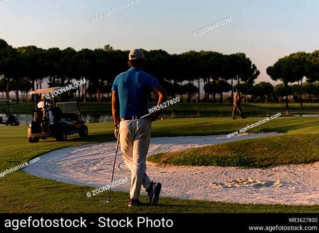 golfer from back looking to ball and hole in distance, handsome middle eastern golf player portrait from back with beautiful sunset in background