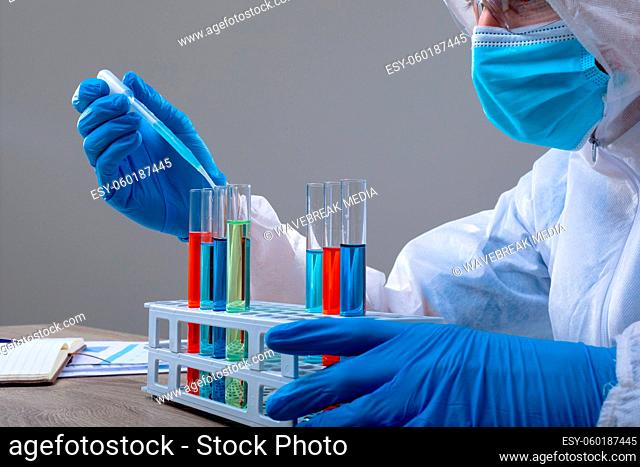 Caucasian male doctor wearing ppe suit holding test-tubes