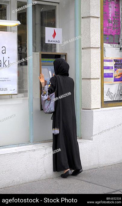 Austria, Vienna, Musliemin in black burqa at Gedautomat, Europe