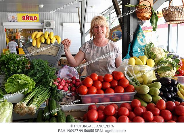 25 July 2019, Russia, Simferopol: The saleswoman Elmira stands behind her stand in the market hall where she sells tomatoes and peaches from the Black Sea...
