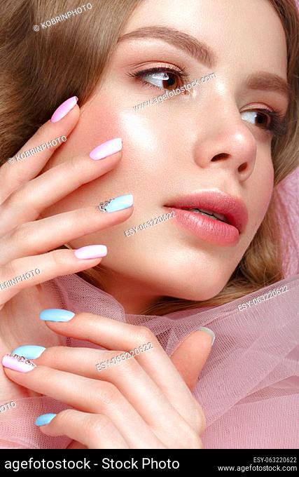 Beautiful girl with light make-up and gentle manicure in pink clothes. Beauty face. Design nails. Photo taken in studio on pink background
