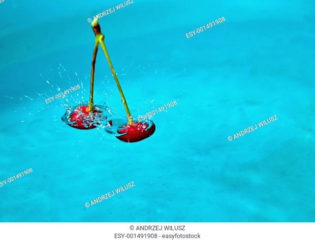 cherry fruti droping into water against blue background