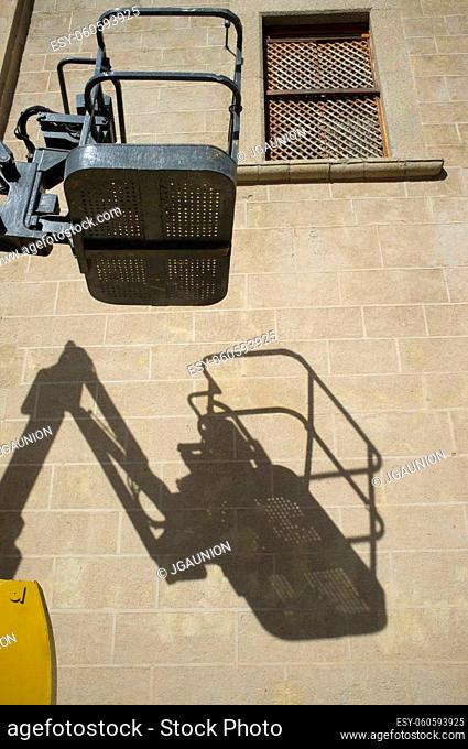 Self-propelled articulated boom lift at work. Basket on shadows