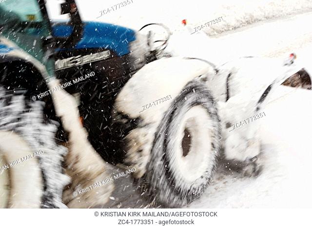 Tractor with snowplow in Scandinavian winterstorm